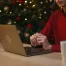 woman using laptop, sitting in front of Christmas tree