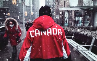 person wearing red Canada jacket, walking down city street