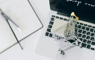miniature shopping cart and package on top of laptop computer