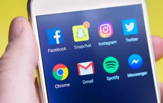 up-close view of hand holding smartphone displaying social media app icons