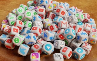 pile of dice, each decorated with a different social media platform logo