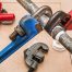 wrenches on pipe, with other plumbing tools and supplies in background