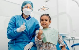 dentist and child patient giving “thumbs up” sign