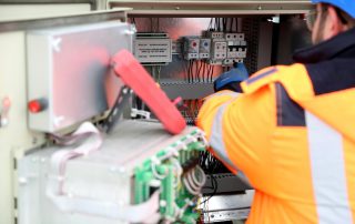over-the-shoulder view of electrician working on large electrical panel